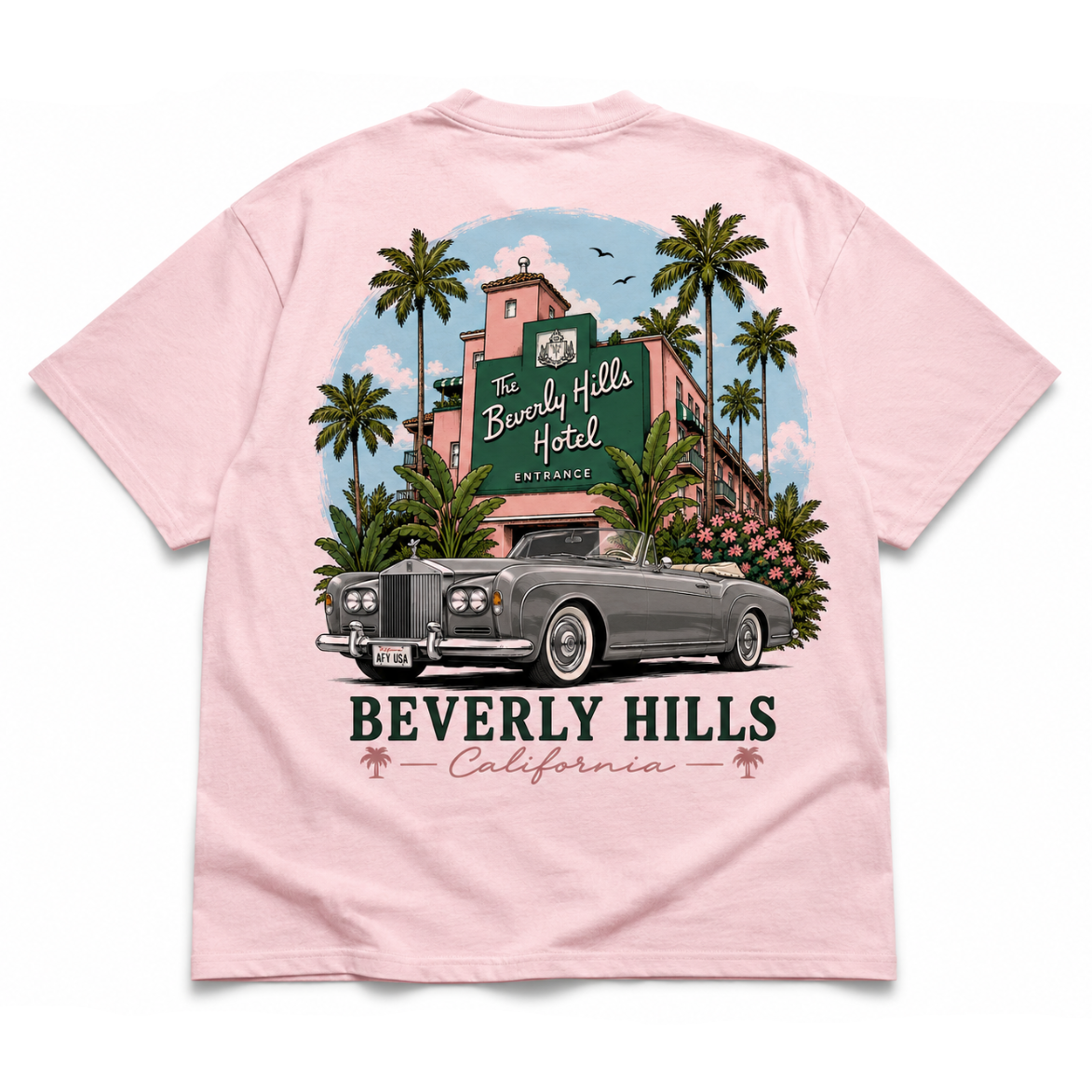 A light pink short-sleeve t-shirt shown flat against a white background, featuring a large graphic print on the front. The graphic depicts a vintage gray convertible car parked in front of a pink Beverly Hills Hotel building surrounded by palm trees, with the text 'BEVERLY HILLS California' printed below.